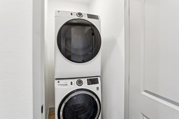 A white front load washing machine in a laundry room.